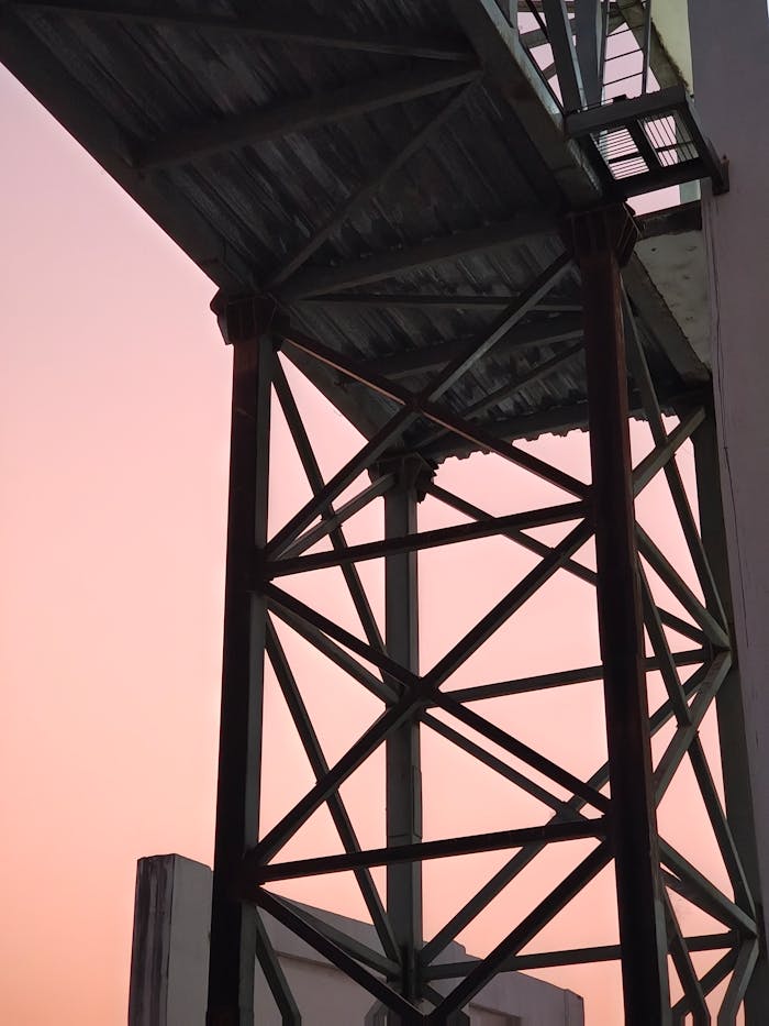 A metal structure silhouetted against a pastel sunrise sky, capturing industrial aesthetics.
